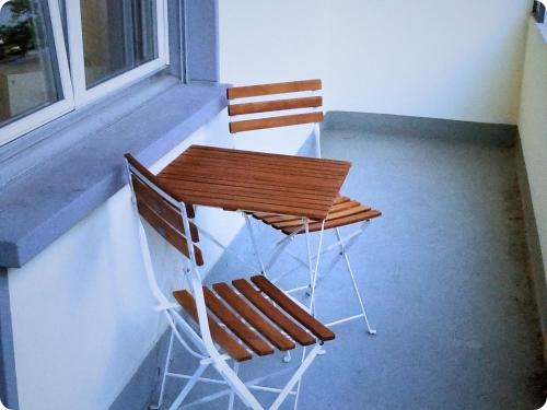 two chairs and a wooden table on a porch at HSH Monbijou - Serviced Junior Suite with balcony Bern City in Bern