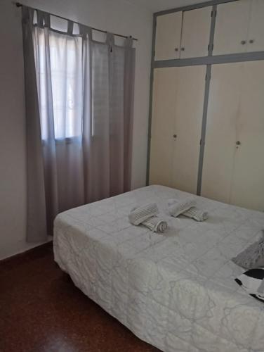 Un dormitorio con una cama blanca con una ventana. en Sarratea 1427, en Santiago del Estero