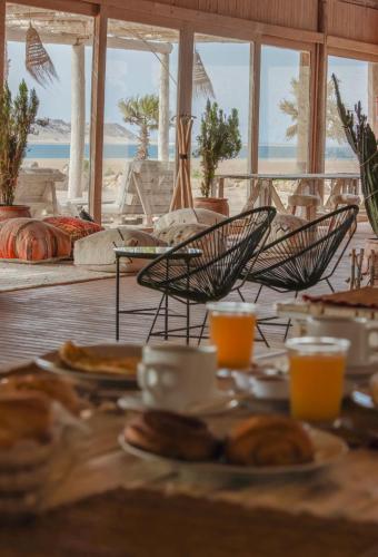 a table with plates of food and chairs with a view of the beach at Desert Sands Dakhla Lagoon View & Kitesurf Spot in Dakhla