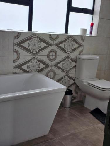 a bathroom with a white tub and a toilet at El-Gibbor Residence 1 in Ermelo