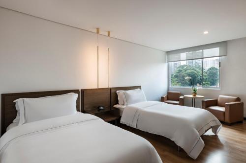 a hotel room with two beds and a window at Hotel Poblado Alejandria in Medellín