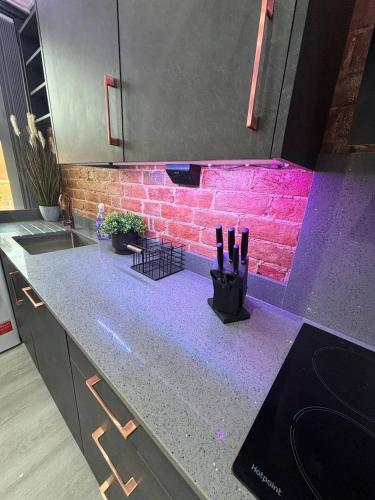 eine Küchentheke mit einem violetten Licht an einer Ziegelwand in der Unterkunft Modern 3bed | 3en-suite | Garden in Reading