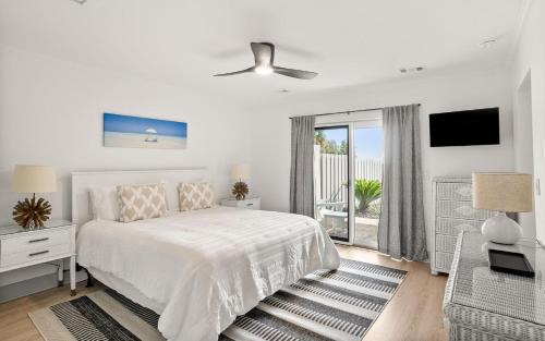 a white bedroom with a bed and a balcony at 401 Captain John Fripp Villa in Fripp Island
