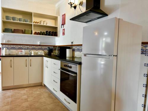 a kitchen with white cabinets and a refrigerator at Égua Nature House in Piódão