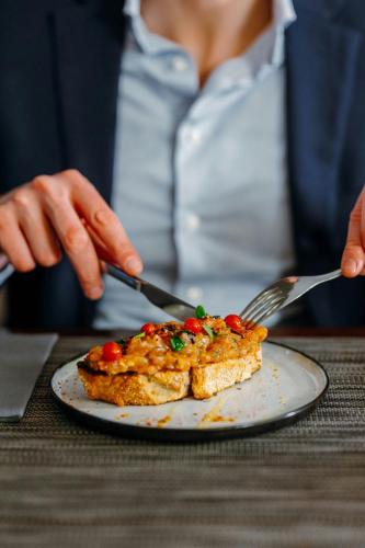 a person holding a fork and knife and a plate of food at Sheraton Brussels Airport Hotel in Zaventem