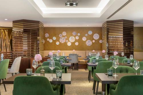 a dining room with tables and green chairs at Sheraton Brussels Airport Hotel in Zaventem