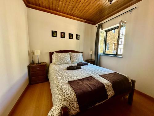 a bedroom with a bed with a wooden ceiling at Égua Nature House in Piódão