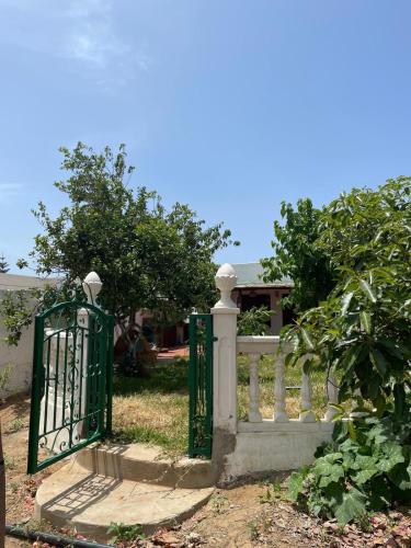 a white fence with a green gate in front of a house at Fluture in Larache