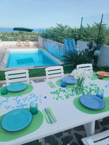 a table with plates and chairs next to a swimming pool at Comfort &Relax B&B&Spa in Villa Rosa