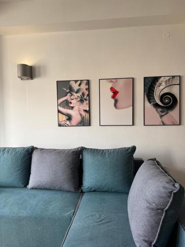 a living room with a blue couch with four pictures on the wall at Apartment CityHeart in Ohrid