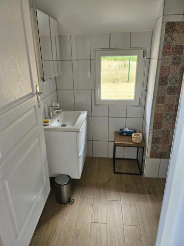 a white bathroom with a sink and a window at Petite sologne in Clémont