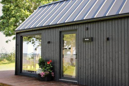 a black shed with a metal roof and windows at Mirage - Dreamy Seaside Design Cabin in Engure