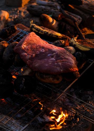 a steak and sausages cooking on a grill at Samas Lasal - Hotel La Saladita in Temalhuacán