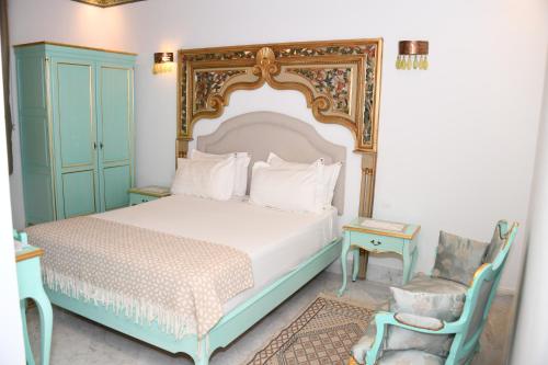 a bedroom with a large bed and a chair at Dar Hamouda Guest House - Médina de Tunis in Tunis