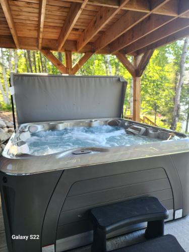a hot tub on a patio with a wooden roof at La Belle Vie in Saint Ludger de Milot