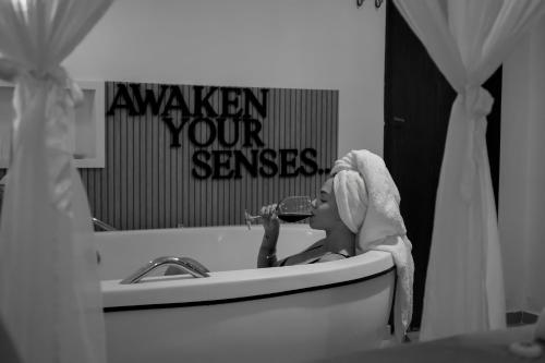 a woman sitting in a bath tub drinking a glass of wine at Xamã Senses - Hotel Pousada in Pipa