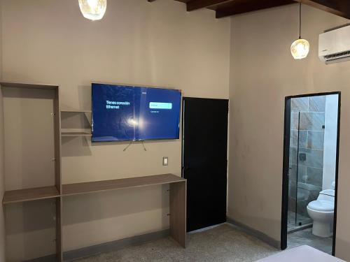 a bathroom with a tv on a wall with a toilet at Casa Kyros Boutique in Medellín