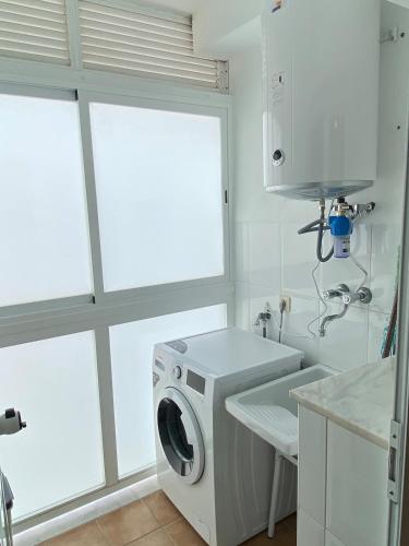 a washer and dryer in a white kitchen with windows at PUEBLO MAR - Apartamento en la Marina Alta in Pego