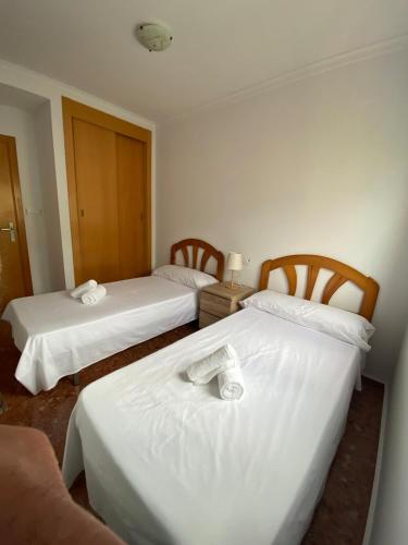 a hotel room with two beds with white sheets at PUEBLO MAR - Apartamento en la Marina Alta in Pego