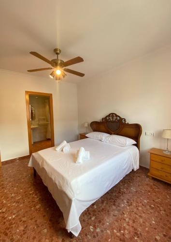 a bedroom with a large white bed with a ceiling fan at PUEBLO MAR - Apartamento en la Marina Alta in Pego