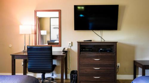 a room with a desk and a television on a wall at Super 8 by Wyndham Kingston in Kingston