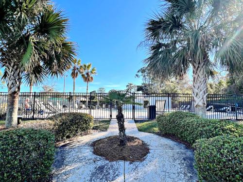 a walkway with palm trees and a statue in a park at Bayview in Orange Beach