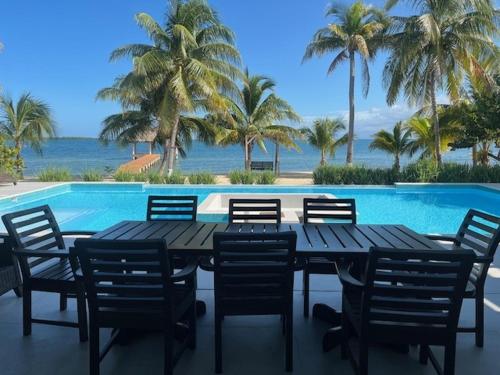 a wooden table and chairs next to a swimming pool at Casa de Wilson - 5 Bedroom Beachfront Villa in Maya Beach