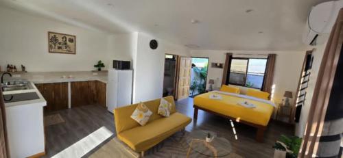 a living room with a yellow couch and a kitchen at Tahiti Kalihi Lodge in Faremi