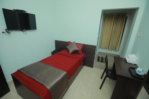 a bedroom with a bed and a desk and a television at Premier Tourist Home in Kunnamkulam