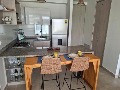 a kitchen with a wooden island with two bar stools at Apartamento Cartagena cerca a la playa in Cartagena de Indias
