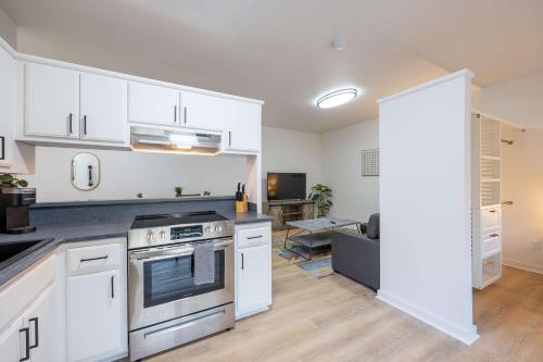 een keuken met witte kasten en een kookplaat oven bij Modern Downtown Studio - Bike or Walk to Trails & Dining in Bentonville