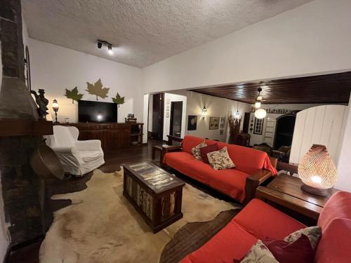 a living room with a red couch and a tv at Casa em Itaipava Piscina Lareira e Pet Friendly in Petrópolis