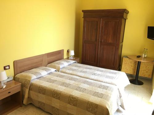a bedroom with two beds and a wooden cabinet at Il Leone D'Oro in Telgate