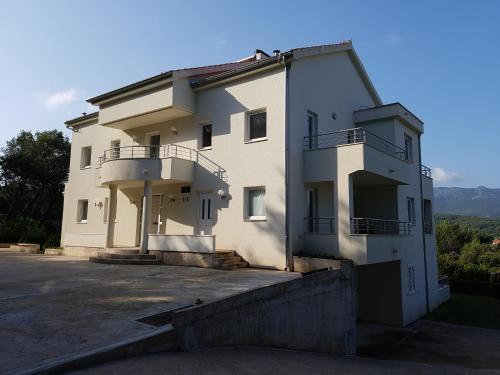 a large white building with a balcony on it at Apartments Villa Maslinica in Vrboska