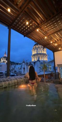 a woman in a swimming pool with a building in the background at Hotel Spa Casa del Sol in Guanajuato