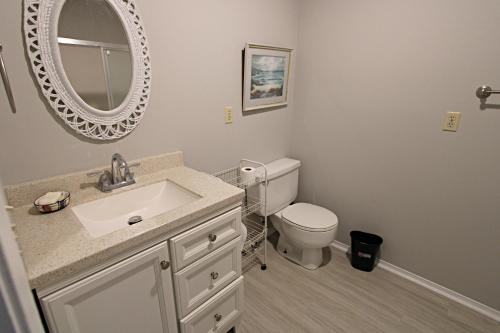 een badkamer met een wastafel, een toilet en een spiegel bij Silver Sands North in Gulf Shores
