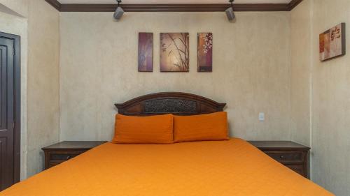 an orange bed in a bedroom with two pictures on the wall at Sonoran Sky in Puerto Peñasco