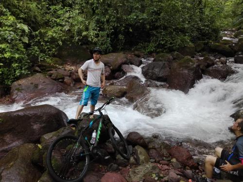 a man standing on rocks near a river with a bike at casa blanca in Restrepo