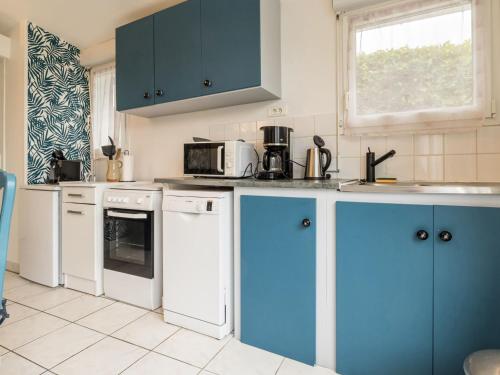 une cuisine avec des armoires et des appareils bleus et blancs dans l'établissement Gîte indépendant avec terrasse - Proche de St Nazaire et La Baule, au cœur du Parc de Brière - FR-1-306-862, à Saint-Malo-de-Guersac