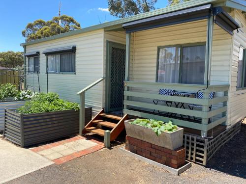 a tiny house with a porch and a garden at Golden Country Motel and Caravan Park in Maryborough