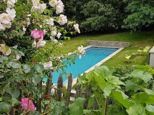 une piscine dans une cour fleurie dans l'établissement Maison rénovée avec piscine et grand jardin, à 2 km de la Vallée de l'Yon - FR-1-426-329, à Le Tablier