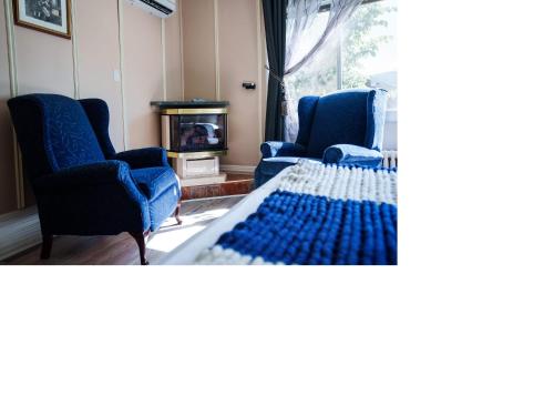 a living room with two blue chairs and a table at Hôtel-La Grande Maison et Spa in Baie-Saint-Paul