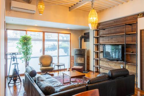 a living room with a couch and a tv at 源泉かけ流し温泉付き一棟貸しVilla GENSEN TWO in Yuzawa