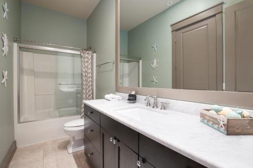 Un baño con lavabo, inodoro y espejo. en Four C's Retreat - Lavish Home with Private Boardwalk Access to the Beach, en Blue Mountain Beach