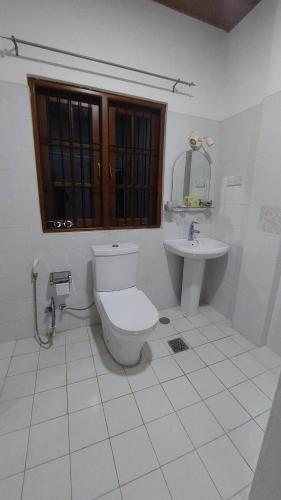 a white bathroom with a toilet and a sink at Honey Dew Villa Minuwangoda in Balabowa