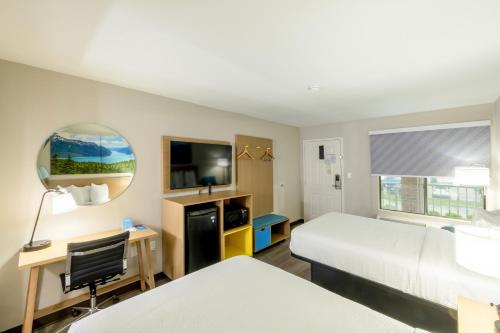 a hotel room with two beds and a desk and a tv at Days Inn & Suites by Wyndham Bossier City - Casino Area in Bossier City