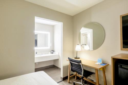a bedroom with a desk and a mirror at Days Inn & Suites by Wyndham Bossier City - Casino Area in Bossier City