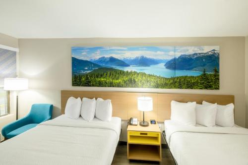 a hotel room with two beds and a painting on the wall at Days Inn & Suites by Wyndham Bossier City - Casino Area in Bossier City