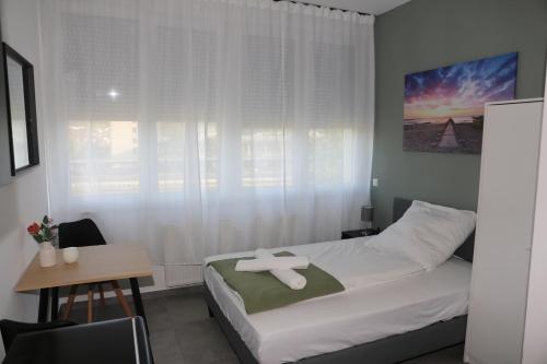 a bedroom with a bed and a table and a window at Ok Apartments in Pforzheim