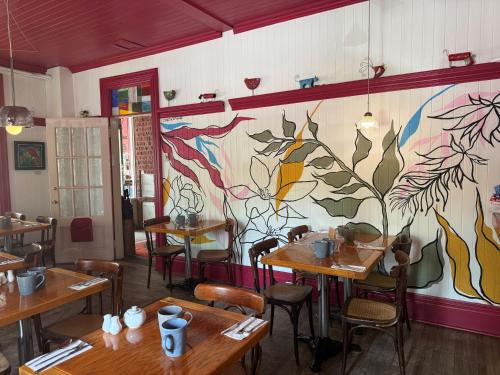 a restaurant with wooden tables and a painting on the wall at Hôtel-La Grande Maison et Spa in Baie-Saint-Paul